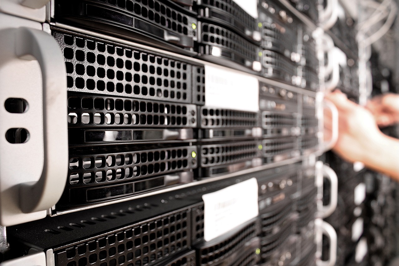 Servereinschübe mit Statusleuchten und einer Hand bei der Arbeit am Rack im Rechenzentrum